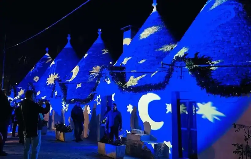 Suggestive lighting di luci blu proiezioni di stelle e lune su tetto di trulli in notturna, evento culturale o decorativo, atmosfera magica e suggestiva, tradizione e innovazione nel design.